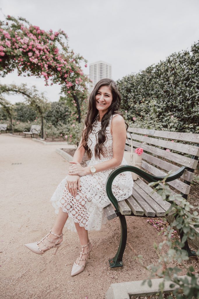 Blogger is modeling a white lace dress while sitting on a bench in the park. Three tiered skirt with nude sheer lining. 5 other Easter dress options.