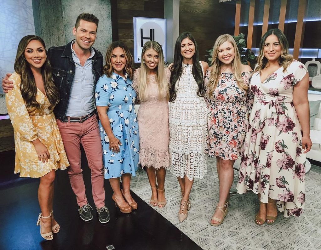 Derrick Shore, Courtney Zavala, and Jenni Metz along with other female models standing in the Houston Life studio. April 9, 2019. White crochet dress, mauve lace dress, floral high-low dress, yellow floral wrap dress.