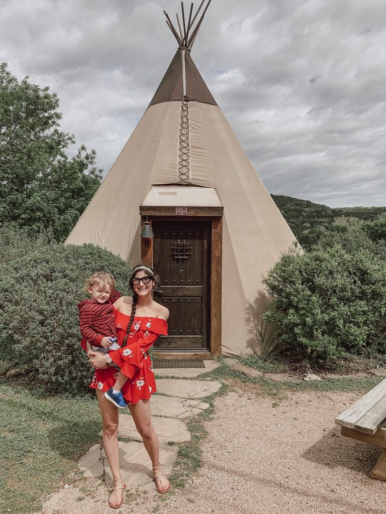 JenniMetz holding son in front of the tipi on the campgrounds.  Tipi camping Texas