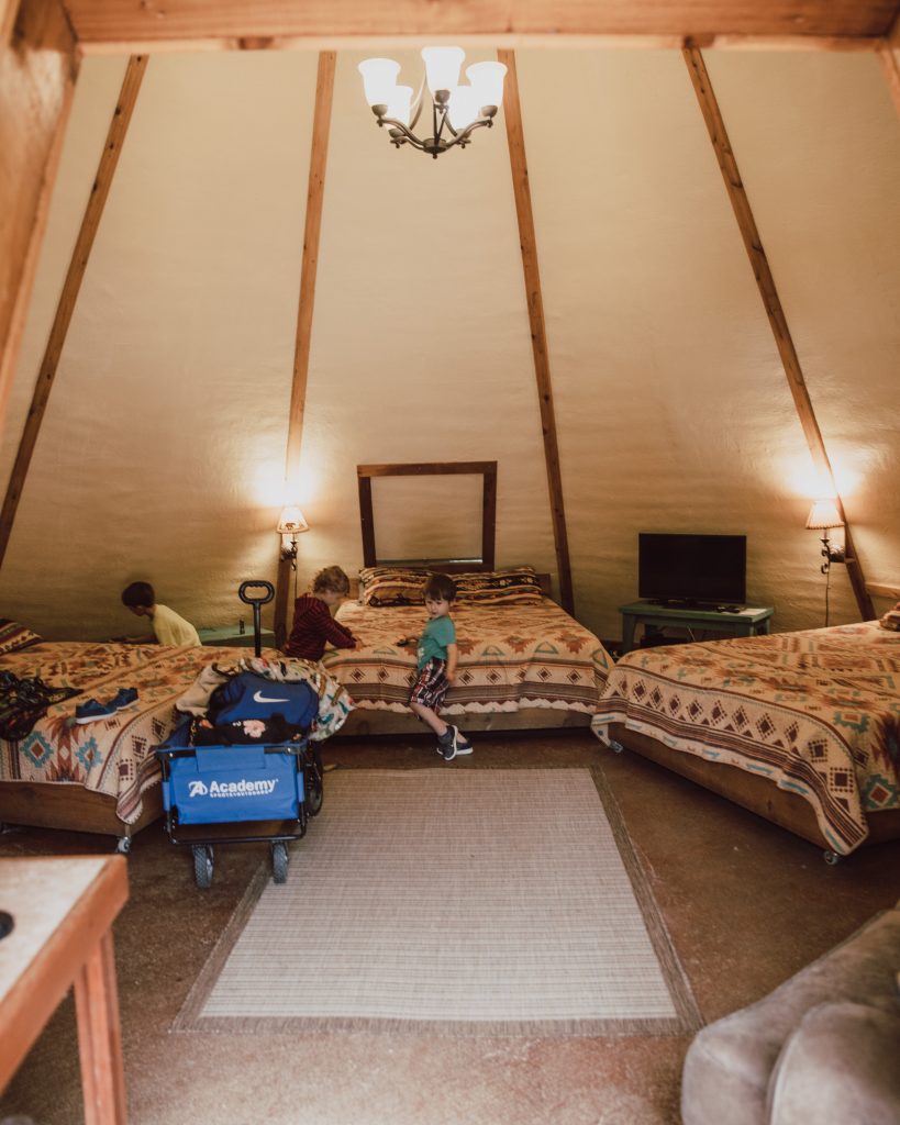 3 full sized beds inside of the tipi camping tent. 3 young boys playing in the tent.  Camping in a Tipi in Texas.
