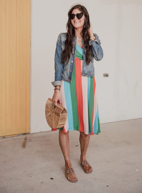 Jenni Metz is wearing a cute striped dress outfit with Tory Burch sandals and a denim jacket.