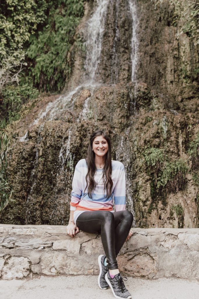 Jenni Metzler, Lifestyle blogger at Japanese tea garden in front of waterfall. 