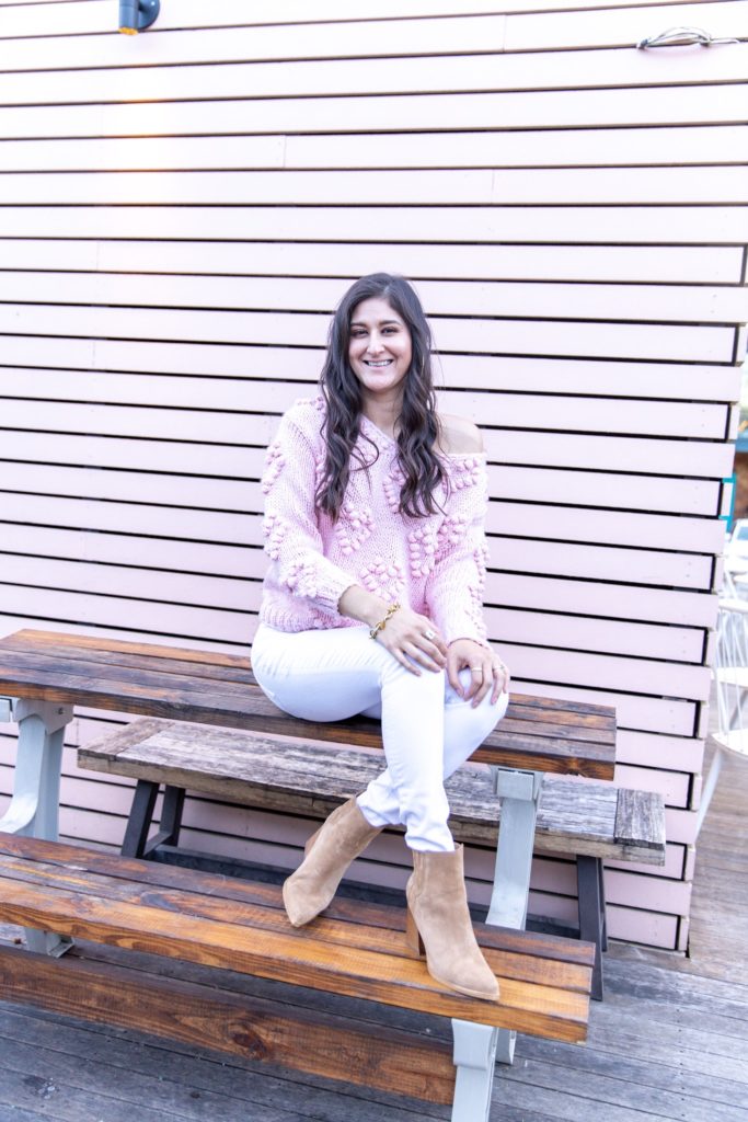 Jenni Metz is wearing a heart pom sweater and white jeans in this post on fall outfit ideas for women. 