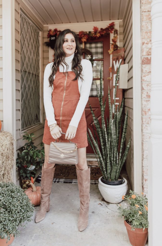 Jenni Metz from The Fashionable Maven blog is wearing a corduroy overall dress and long sleeve turtleneck sweater.