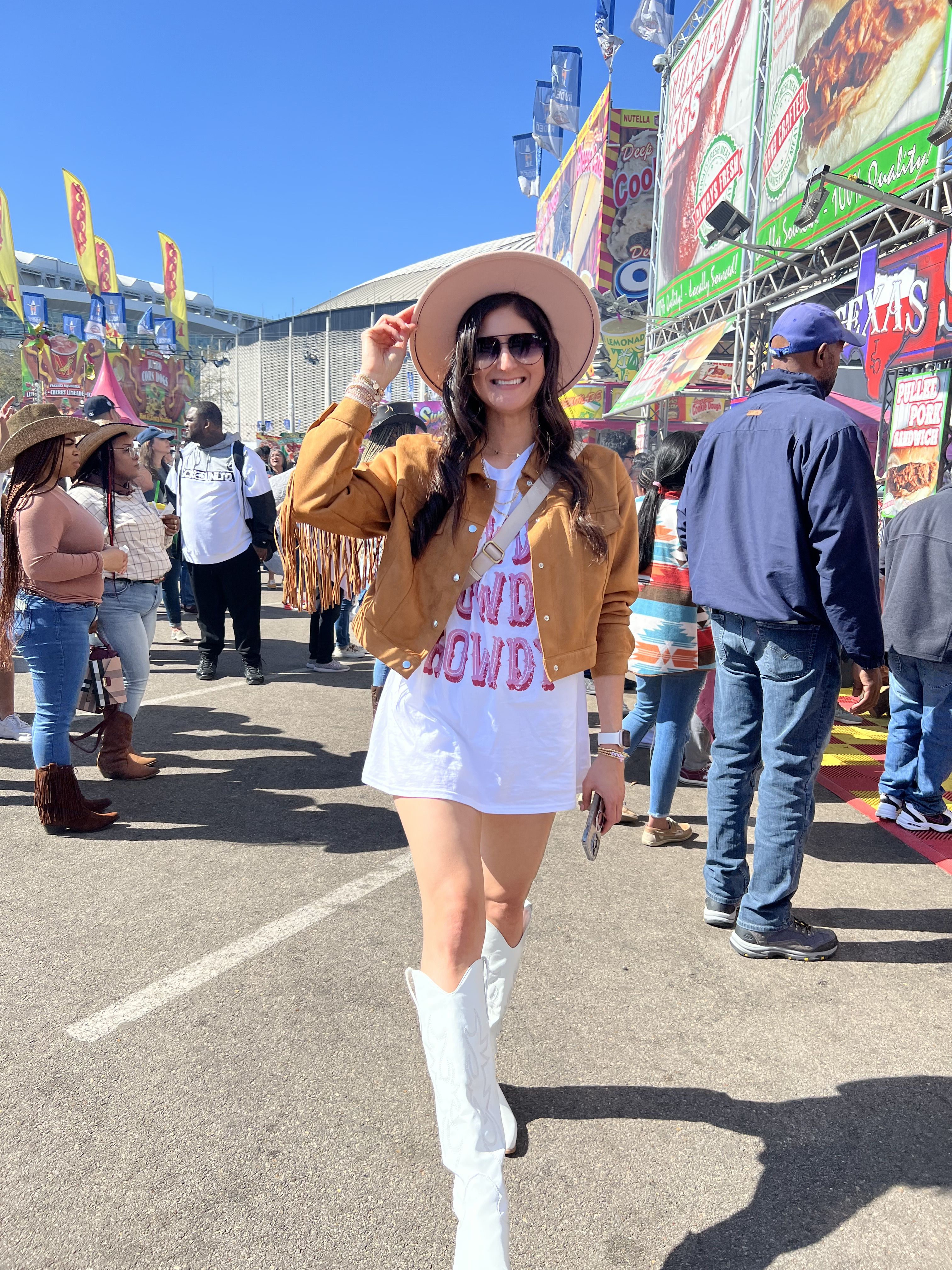 Country concert outfit: Tee shirt that says howdy, suede fringe jacket, white boots, and cowboy hat. Houston Texas